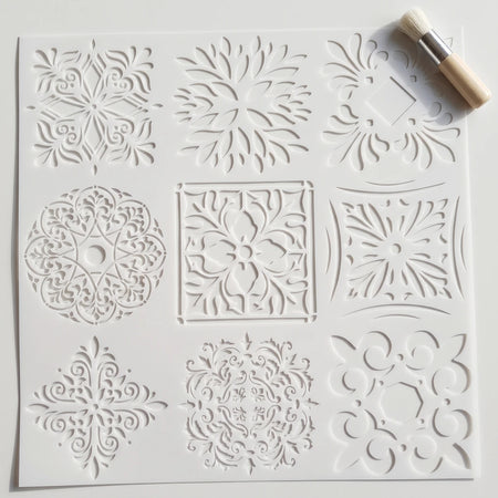 White square 2020-45X45-3 paint stencil featuring nine intricate ornamental patterns, accompanied by a small brush.