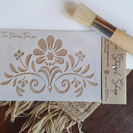 2022-A6-1 paint stencils on a white mylar sheet featuring a floral scroll pattern, top-down view.
