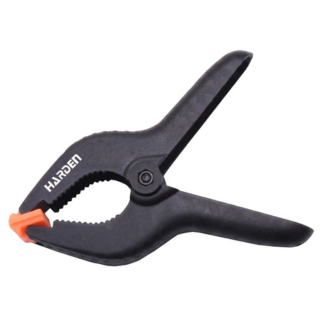 6-inch black plastic spring clamp with orange gripping tips, viewed from a slightly angled side.