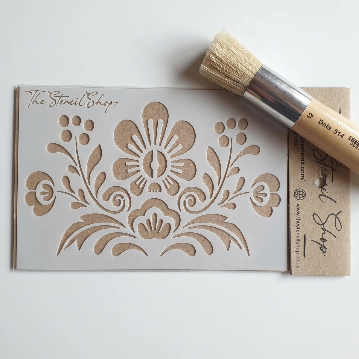 A white A6-9 floral paint stencil from The Stencil Shop, accompanied by a stencil brush, displayed for craft projects.