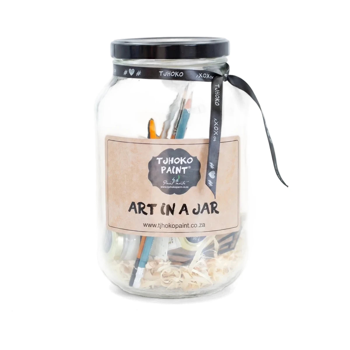 Clear glass Art In A Jar arts and crafts kit with paintbrushes, pencils, and wood shavings, featuring a brown label and