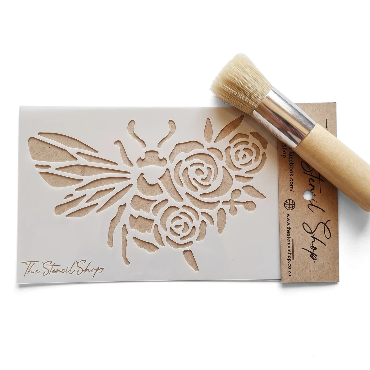 White bee and rose floral paint stencil with a wooden stippling brush on a textured surface, perfect for craft projects.