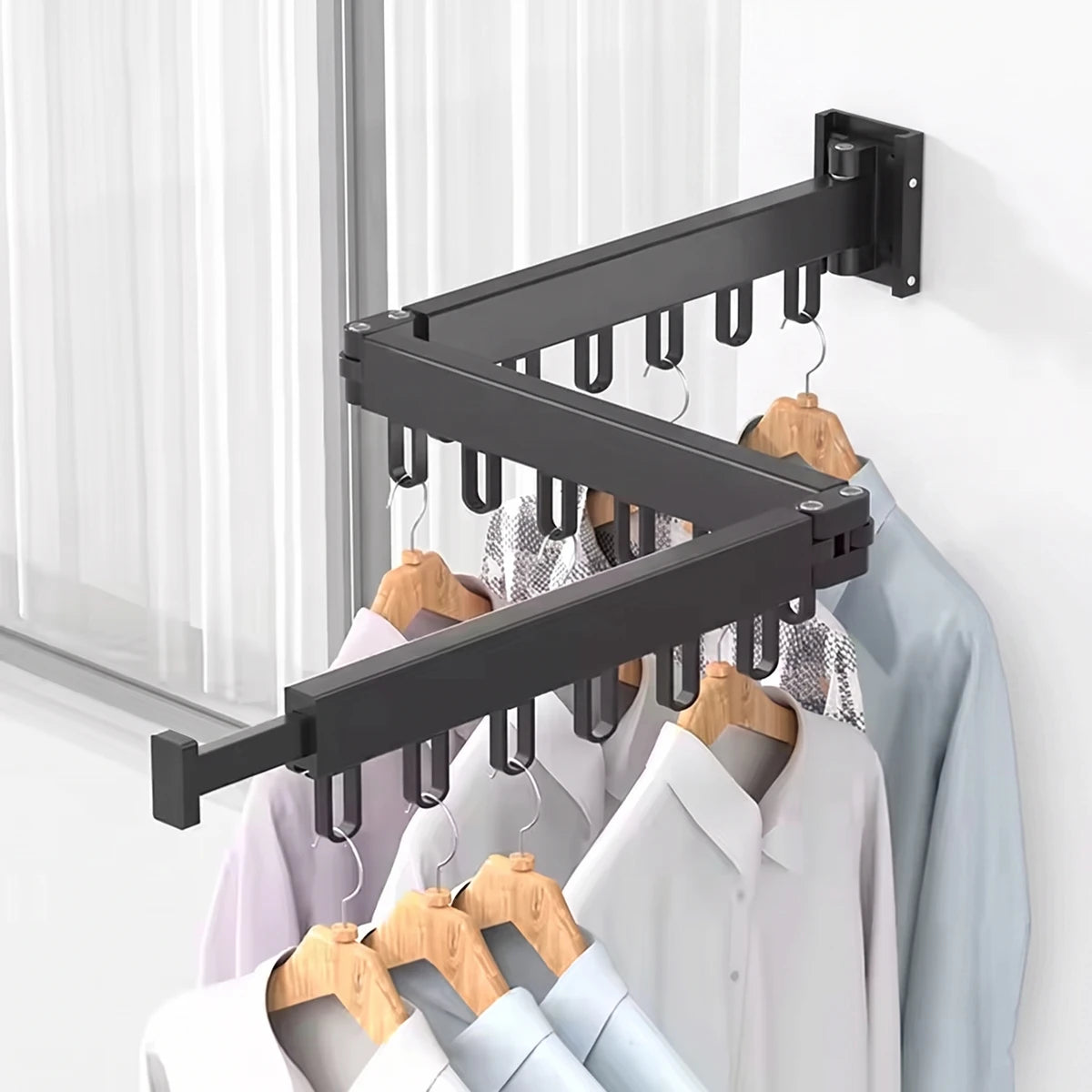 Black foldable wall-mounted drying rack with various clothes hanging on wooden hangers, ideal for compact laundry spaces.