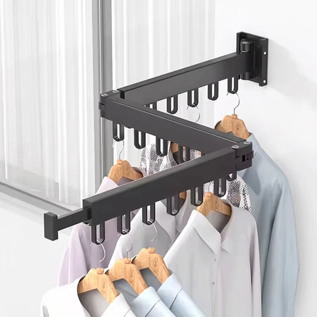 Black foldable wall-mounted drying rack with various clothes hanging on wooden hangers, ideal for compact laundry spaces.