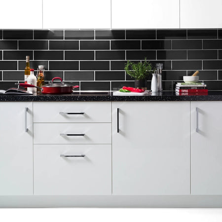 Modern kitchen with black gloss subway tiles backsplash, white cabinets, and black speckled countertop, styled with cooking