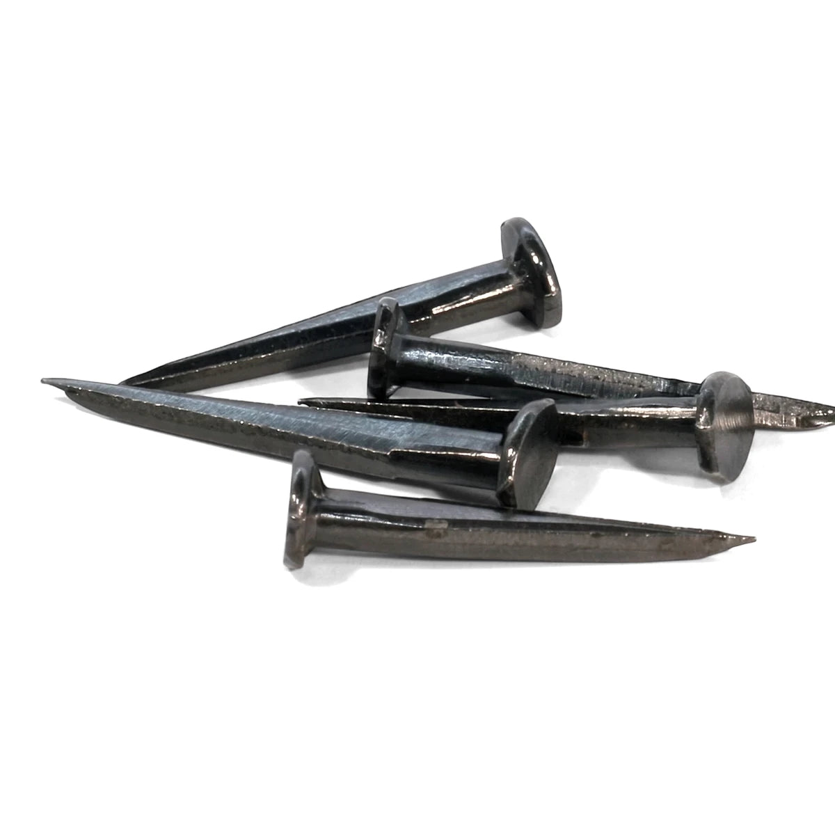 Five dark metallic blue tack nails, 16mm, piled together on a white background, used for construction.