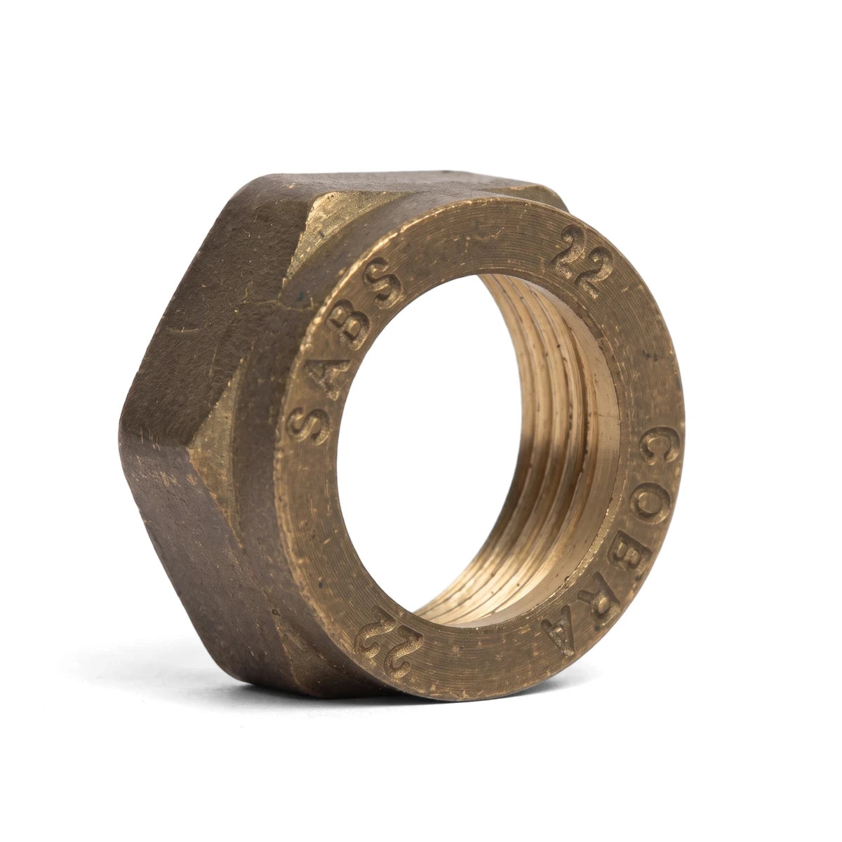 Brass capnut with a hexagonal shape and internal threading, featuring visible markings, viewed from a slightly elevated