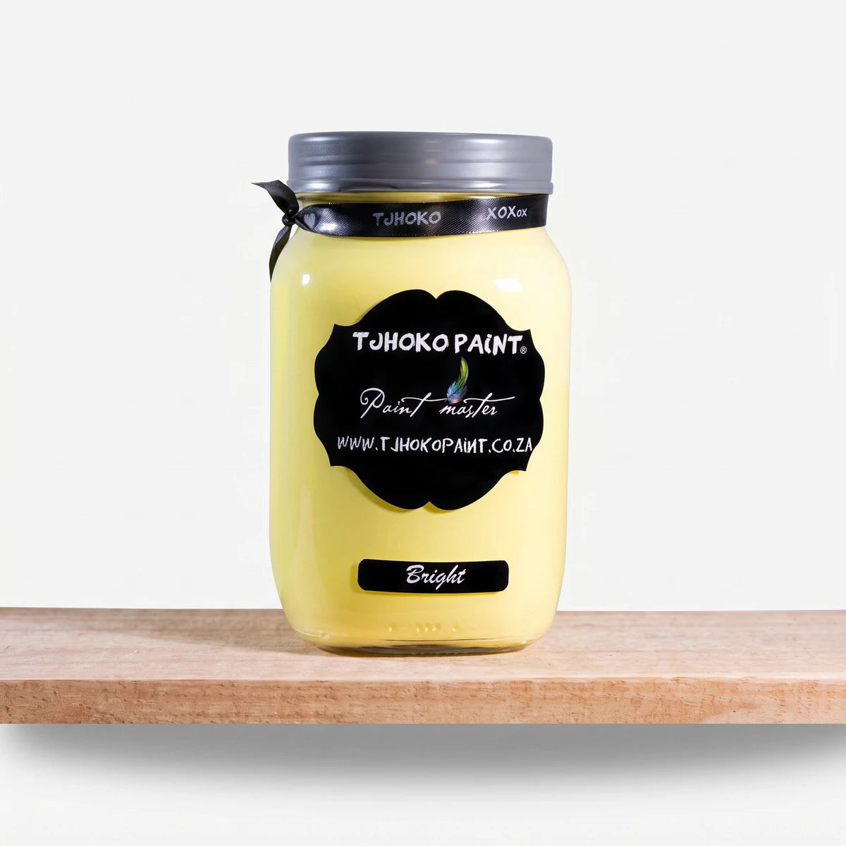 Bright 1L Tjhoko yellow chalk paint in a jar with a black label, resting on a rustic wooden shelf.