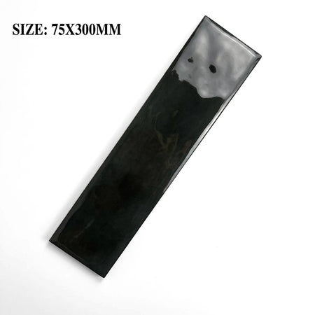 A single dark carbon black glossy ceramic subway tile, measuring 75x300mm, displayed diagonally on a surface.