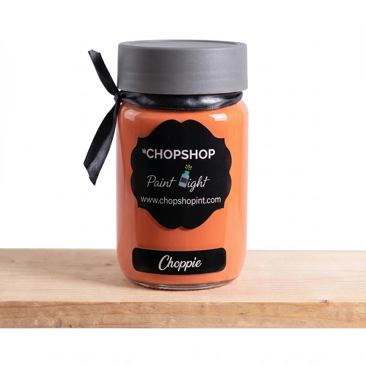 Choppie 250ml paint in an orange jar with a black label, dark grey lid, and black ribbon on a wooden surface.