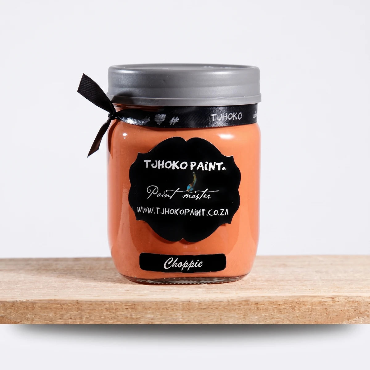 Choppie 500ml Tjohoko Paint in an orange color, visible in a clear glass jar with a black label and grey lid.