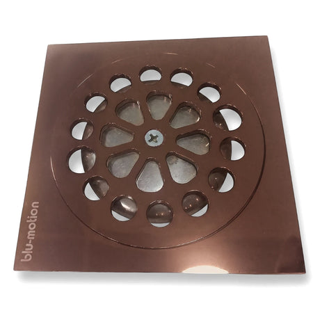Copper square shower drain with a round grate, central screw, and 'blu-motion' logo, viewed from an angle.