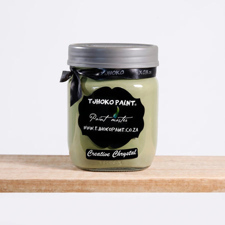 Creative Chrystal 500ml Chalk Paint in an olive green glass jar with a black label, silver lid, and ribbon, on a wooden