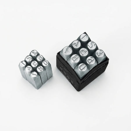Two sets of gray metal number and symbol punch stamps, one loose and one in a black storage case, used for stamping.