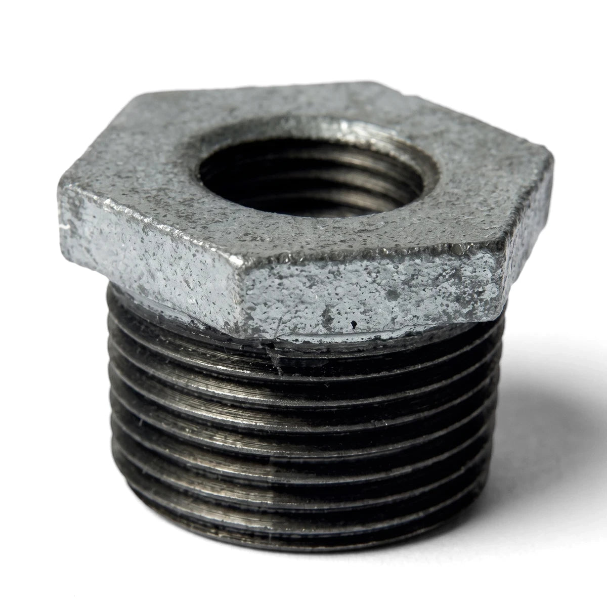 Galvanized M&F reducing bushing, a threaded metal pipe fitting with a hexagonal top, shown in a close-up.