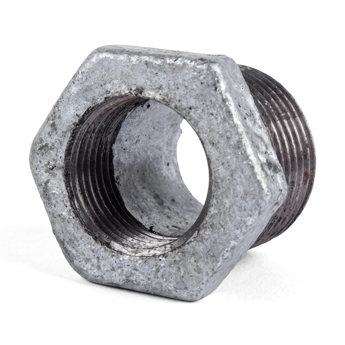 Close-up view of a metal galvanized reducing bush, showing its hexagonal body and threaded interior and exterior for