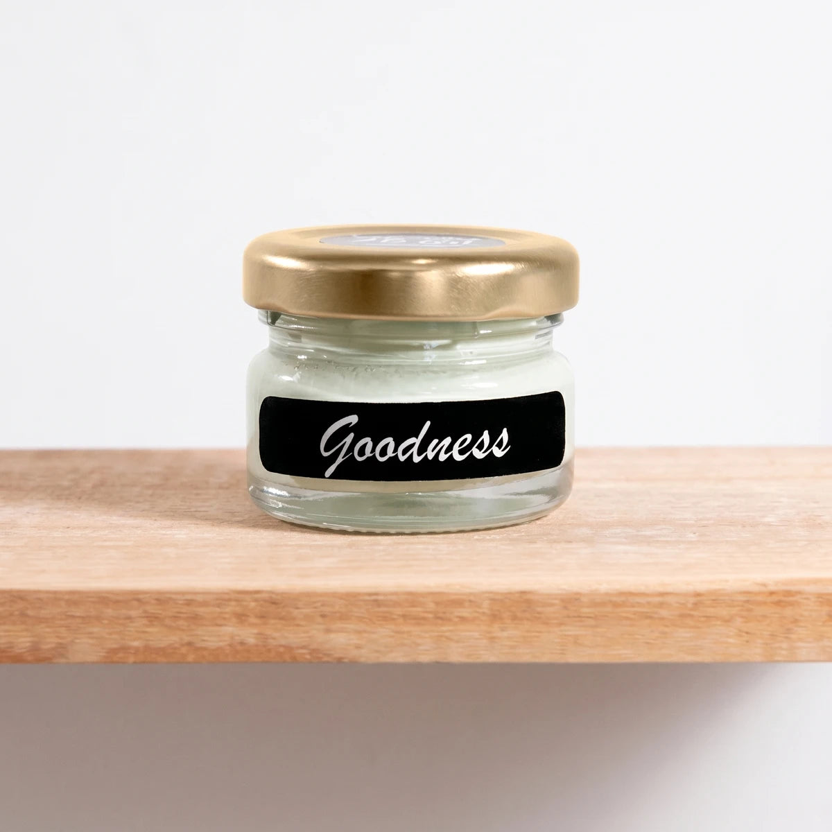 Goodness 25ml Chalk Paint in a small clear glass jar with a gold lid and a black label, displayed on a wooden shelf.