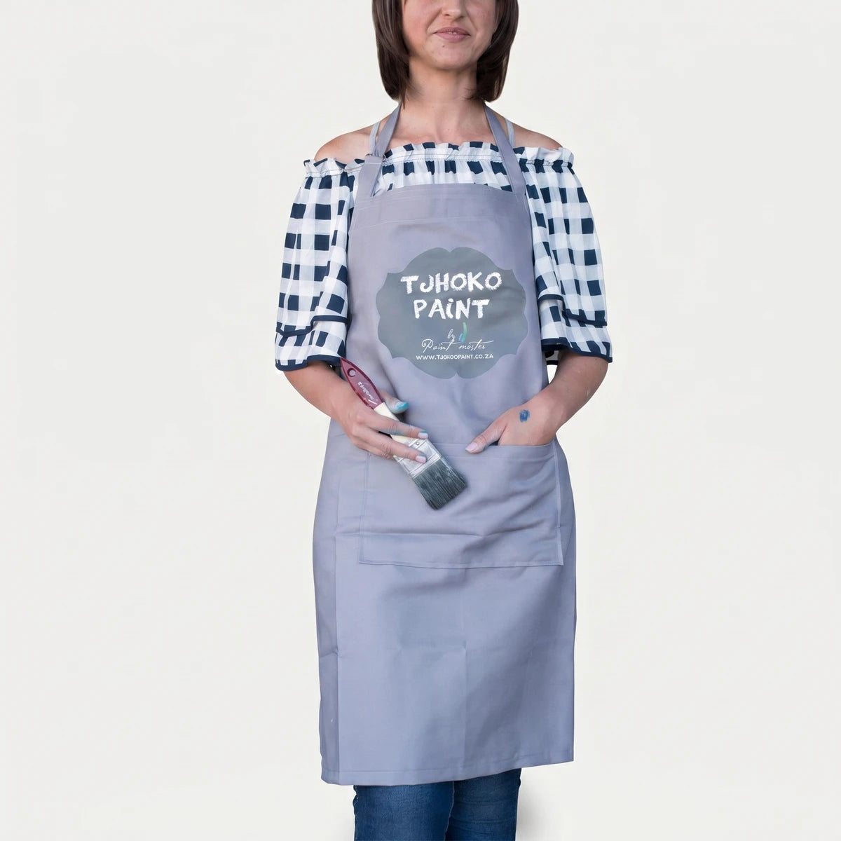 Woman wearing a gray Apron Paint Apron with 'TJOHOKO PAINT' logo, holding a paintbrush.