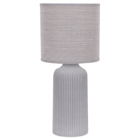 Grey fluted ceramic base table lamp with a cream fabric cylindrical shade, photographed against a white background.