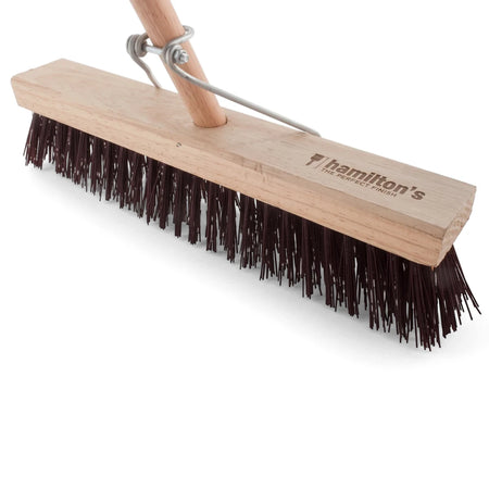 Angled close-up of a Hamilton's wooden platform broom with dark bristles and metal bracket on a white background,