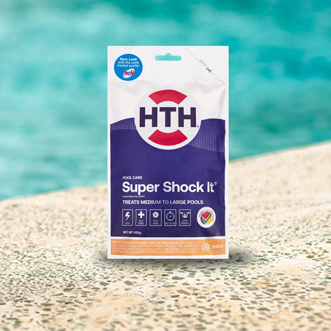 HTH pool care bag labeled shock it on a light stone surface beside a pool