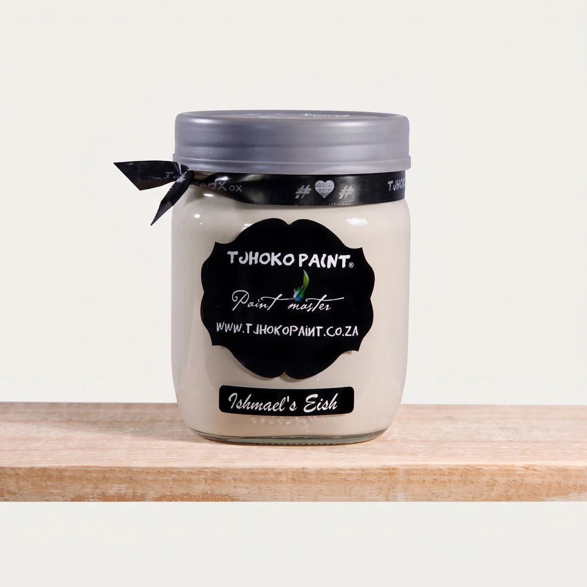 Ishmael's Eish 500ml Tjhoko off-white chalk paint jar with a black label and ribbon, displayed on a wooden shelf.