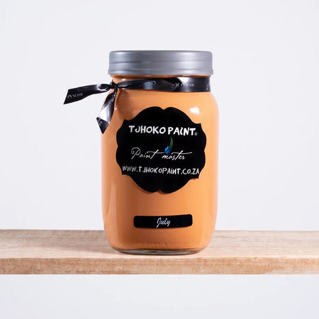 July 1L Chalk Paint in an orange-peach hue, presented in a clear glass jar with a black label on a wooden shelf.
