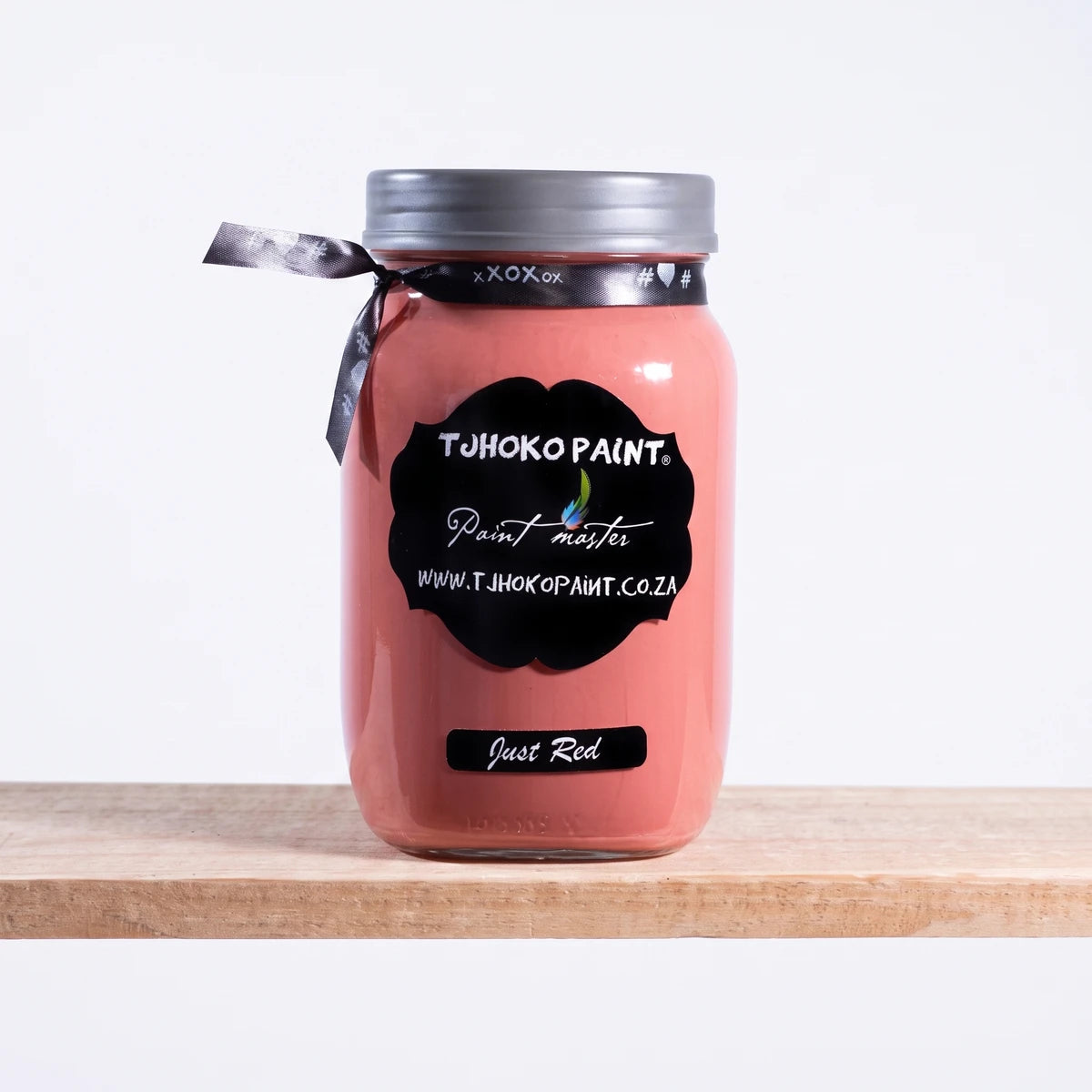 Just Red 1L Tjoko Chalk Paint in a glass jar with a silver lid and black ribbon, displayed on a wooden shelf.
