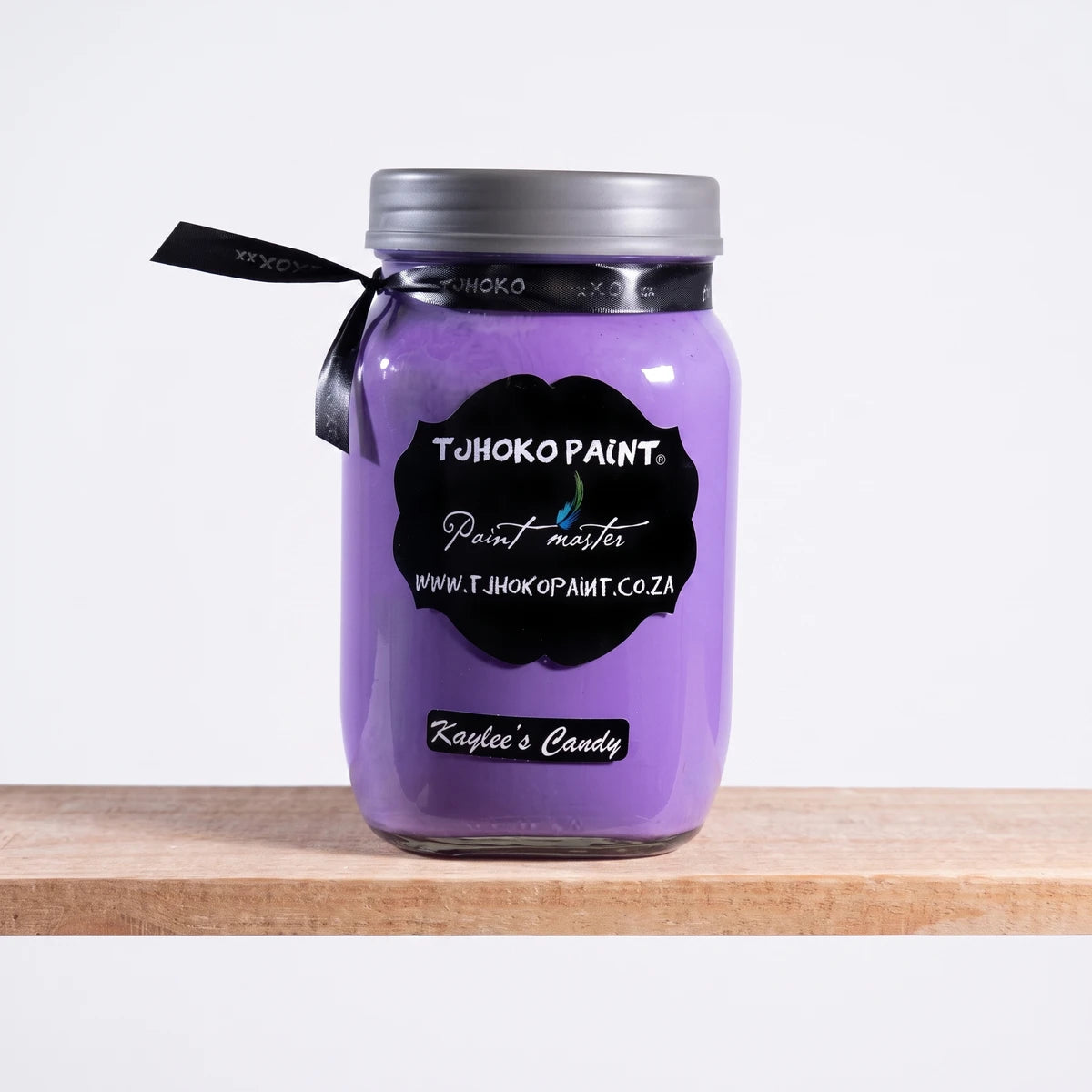 Kaylee's Candy 1L chalk paint in a purple glass mason jar with a black label and ribbon, displayed on a wooden shelf.