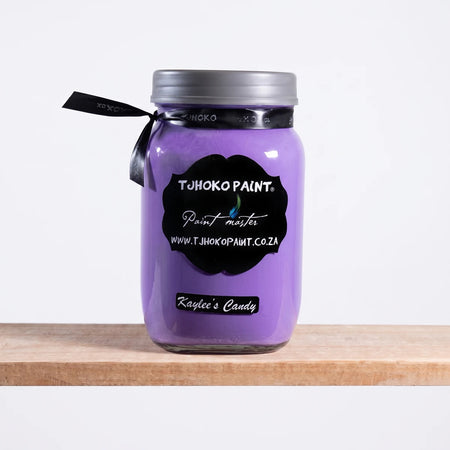 Kaylee's Candy 500ml Tjhoko purple chalk paint jar with a silver lid, black label, and ribbon, on a natural wooden shelf.