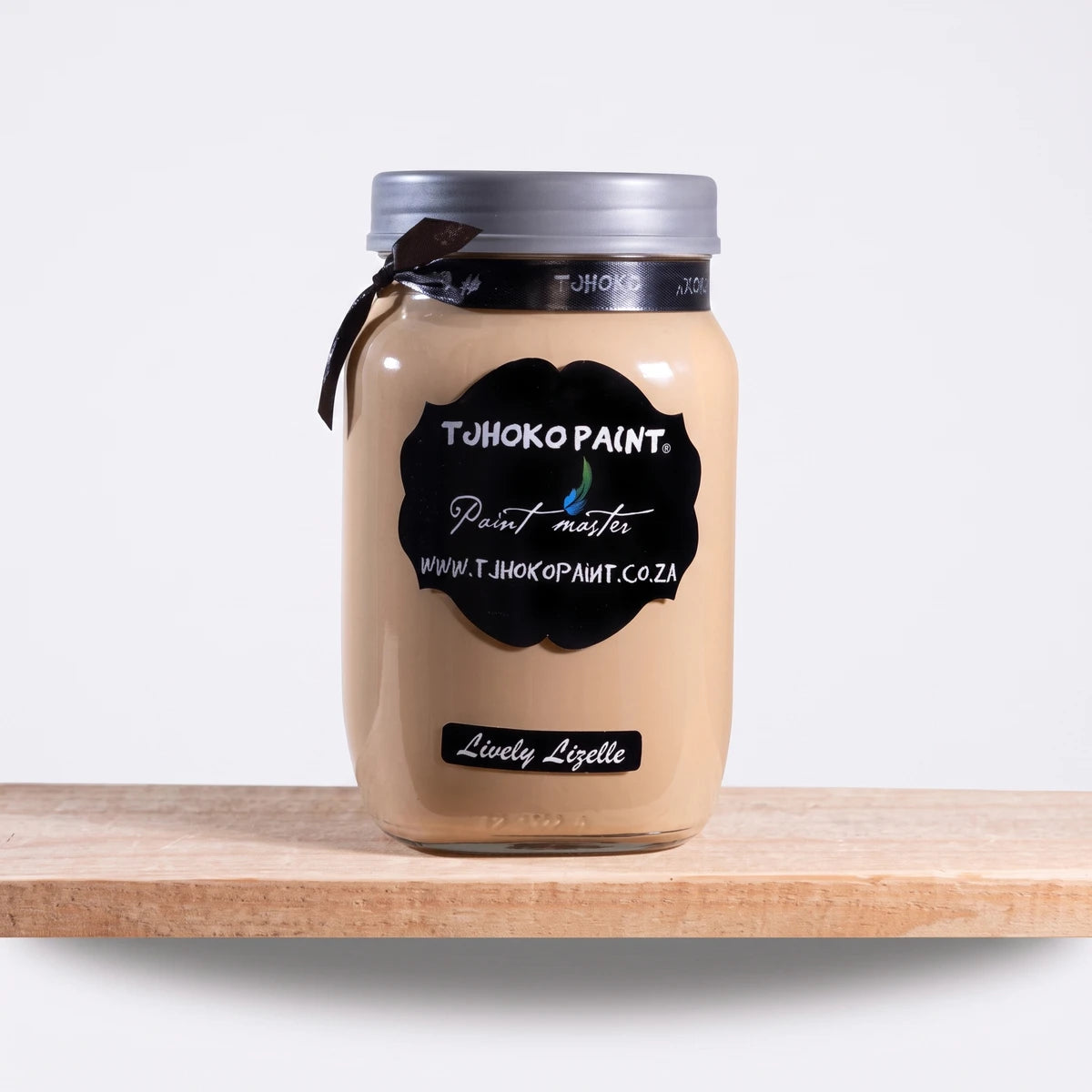 Lively Lizelle 1L Chalk Paint in a clear glass jar with a silver lid, displaying its warm beige hue on a wooden surface.
