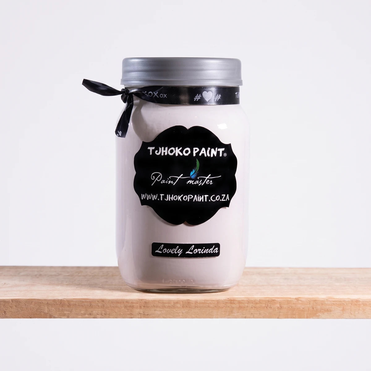A white jar of Tjhoho Paint Lovely Lorinda 1L chalk paint with a silver lid and black label, sitting on a light wooden shelf.