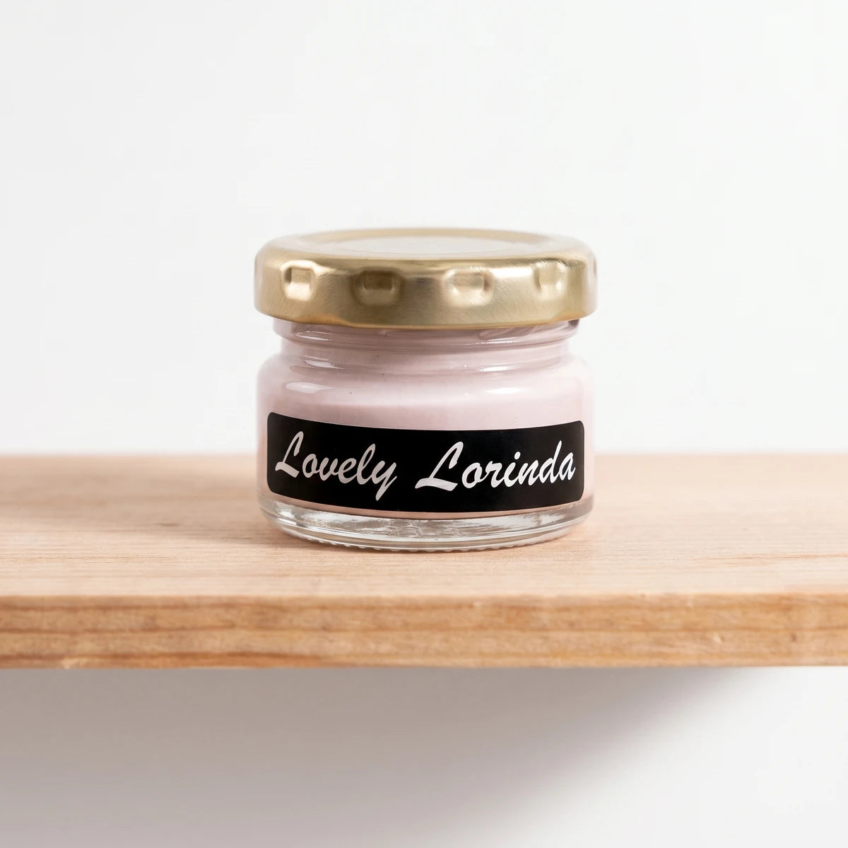 Small glass jar of Lovely Lorinda 25ml light pink chalk paint with a gold lid and black label.