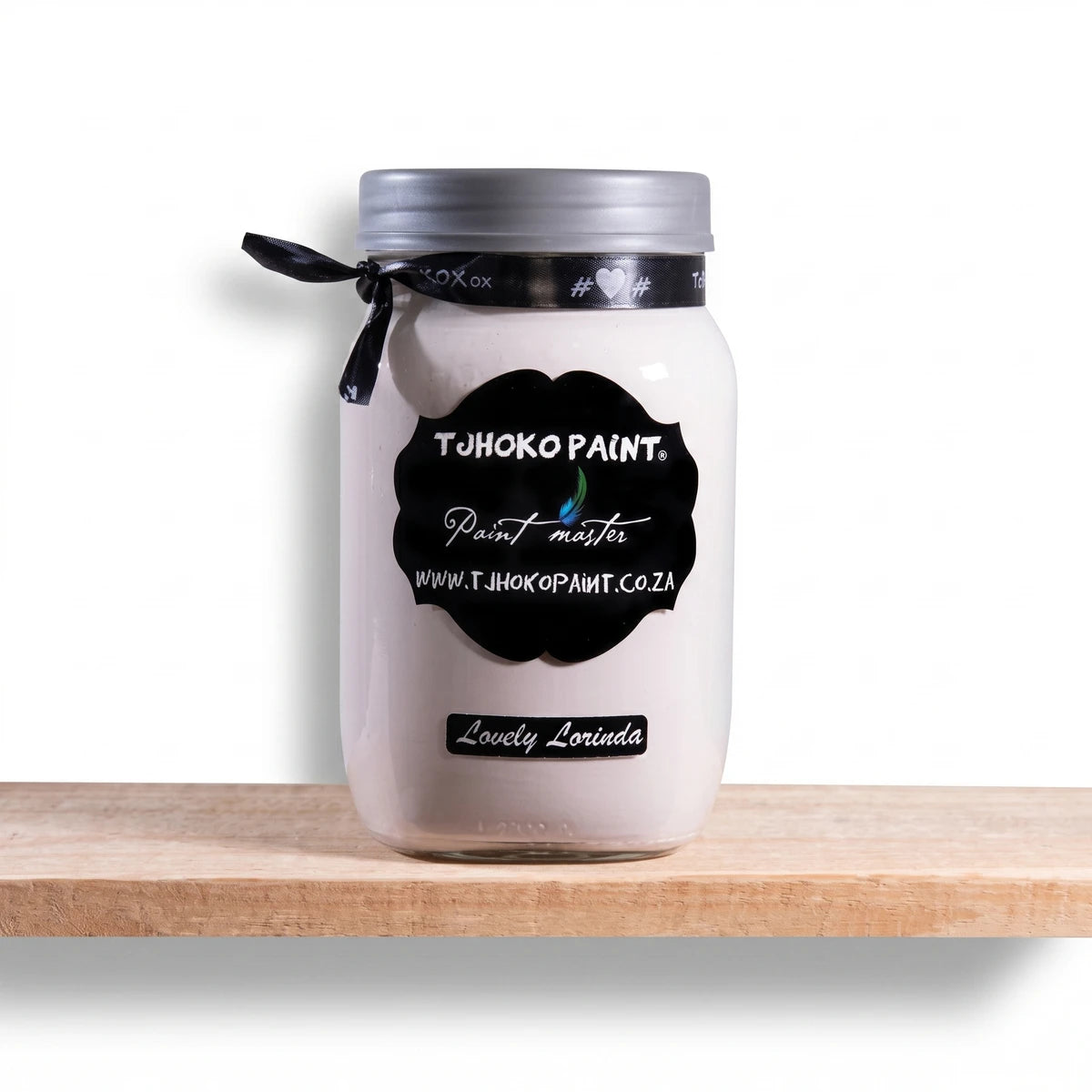 Lovely Lorinda 500ml white chalk paint in a clear glass jar with a silver lid, displayed on a natural wooden shelf.