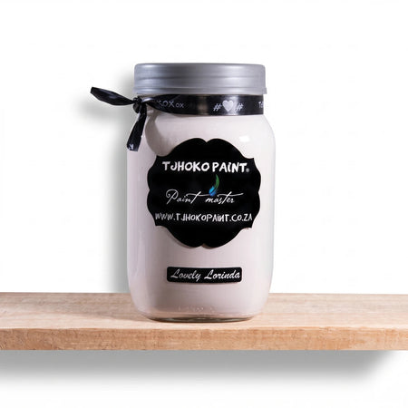 Lovely Lorinda 500ml white chalk paint in a clear glass jar with a silver lid, displayed on a natural wooden shelf.