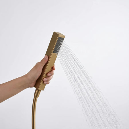Close-up of a hand holding a gold Lux Square Hand Shower with a modern square head, spraying water. Shows the elegant