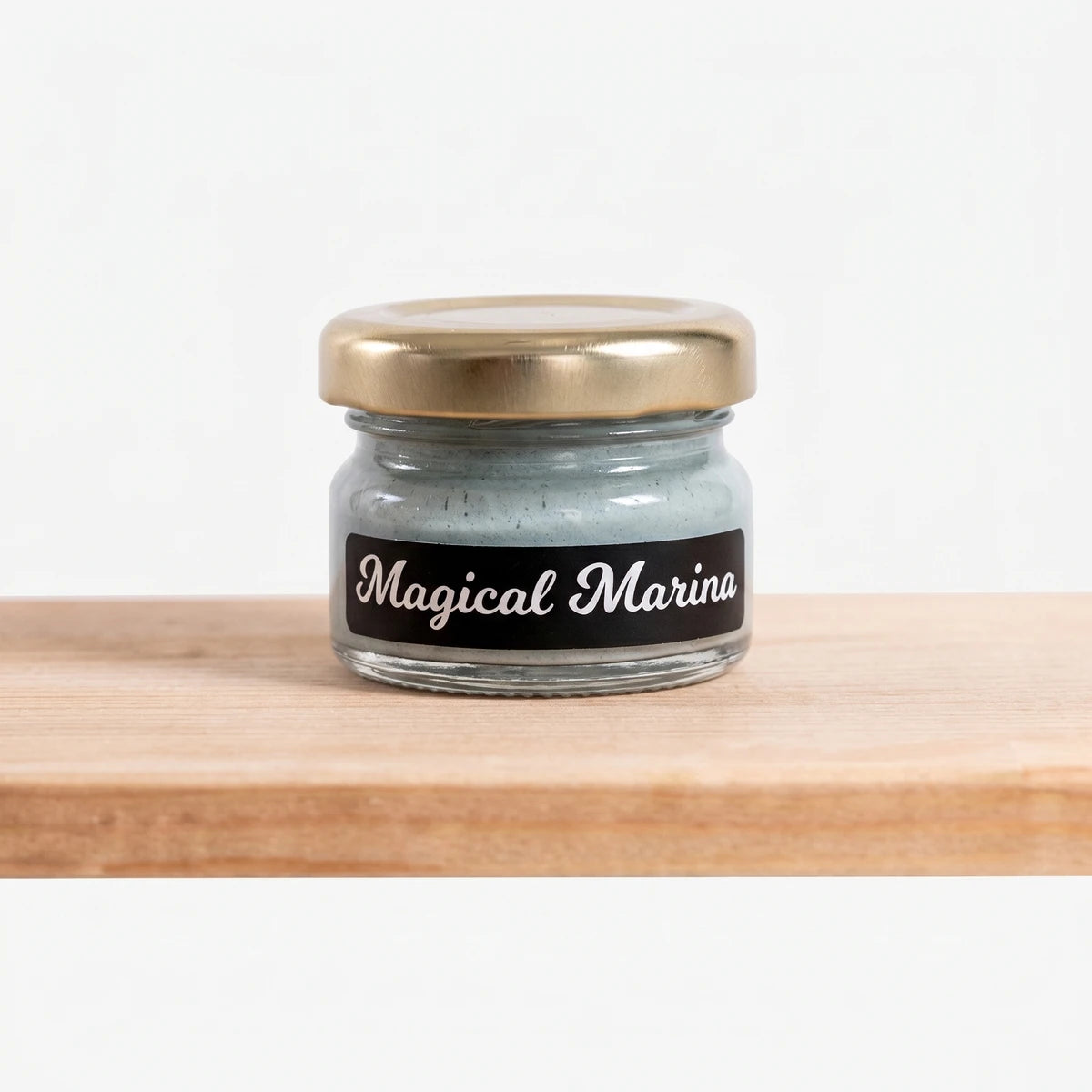 Small Magical Marina 25ml Chalk Paint jar with a gold lid and black label, filled with light blue/grey paint, sitting on a