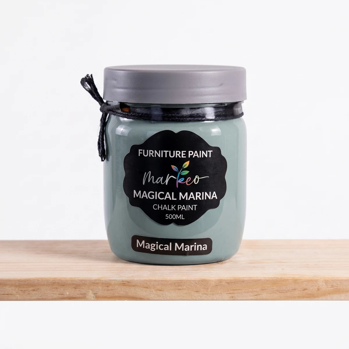 A 500ml jar of Magical Marina chalk paint in a muted teal-green shade, with a black label, on a wooden surface.