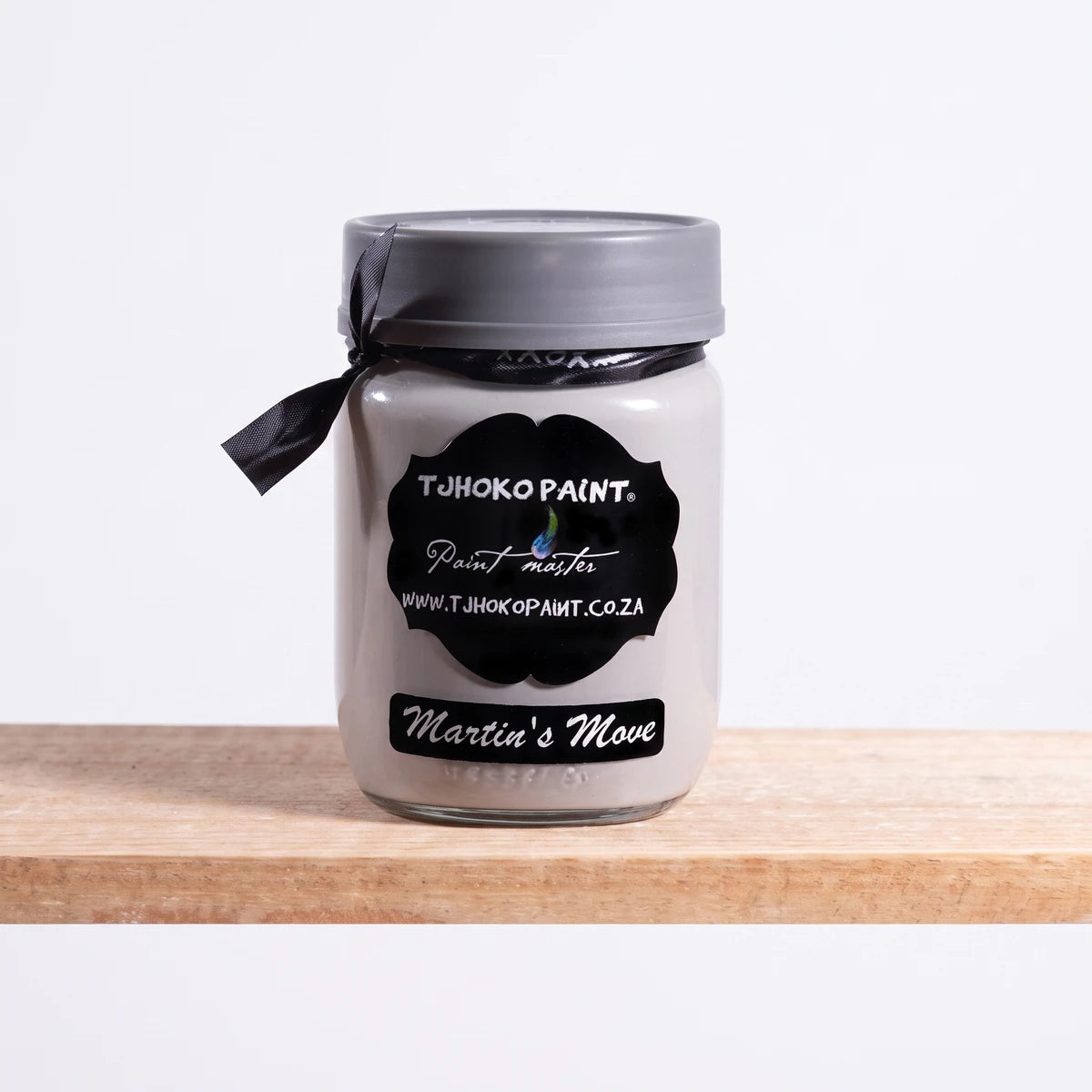 Martin's Move 250ml Tjhoko Chalk Paint in a light grey hue, presented in a glass jar with a black label on a wooden shelf.