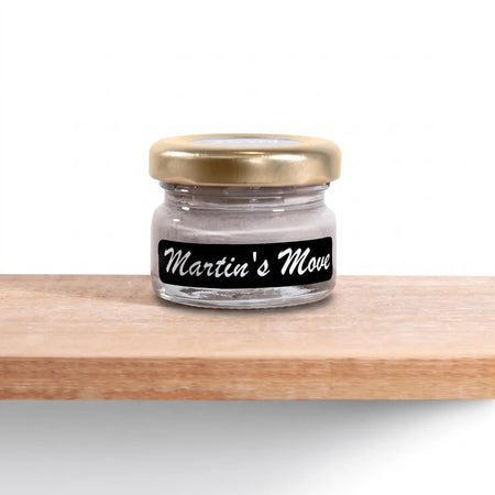Martin's Move 25ml chalk paint jar with a gold lid and black label, filled with light grey paint, displayed on a wooden