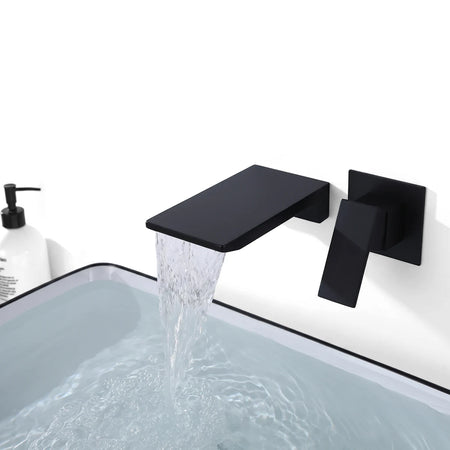 Matte black inwall waterfall mixer faucet with a flat spout flowing into a white rectangular sink, shown mounted on a wall.
