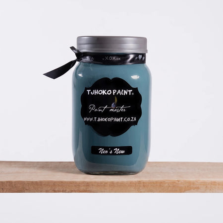 A Neo's New 1L Tjhoko teal chalk paint jar with a black label sits on a wooden shelf against a dark wall.