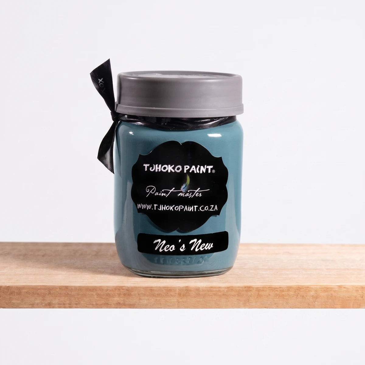 Neo's New 250ml Tjohoko Chalk Paint jar in a tranquil blue-green shade on a natural wooden shelf.