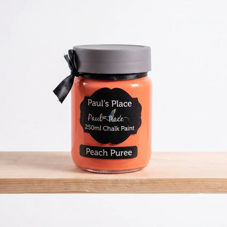 Paul's Place 250ml Chalk Paint in Peach Puree, an orange jar with a black label, displayed on a wooden shelf.