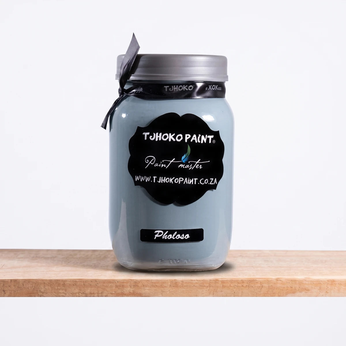 Pholoso 1L Chalk Paint in a light grey-blue glass jar with a black label, silver lid, and grey ribbon, sitting on a wooden