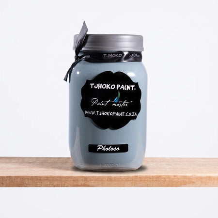 Pholoso 1L Chalk Paint in a light grey-blue glass jar with a black label, silver lid, and grey ribbon, sitting on a wooden