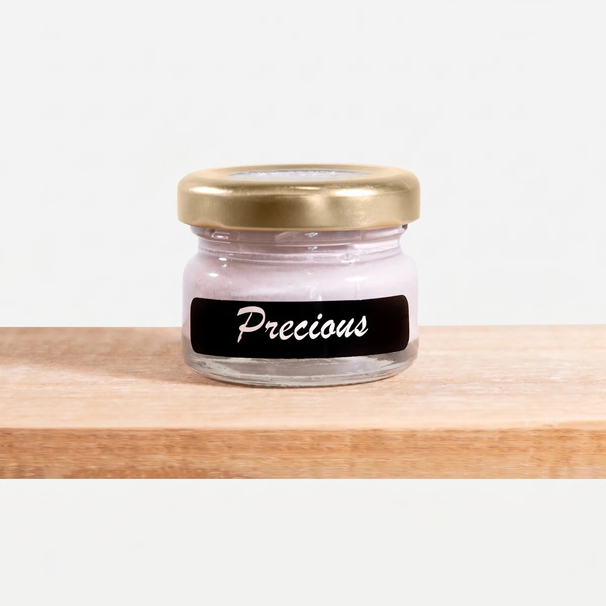 Small glass jar of Precious 25ml Chalk Paint with a golden lid and black label, resting on a wooden surface.