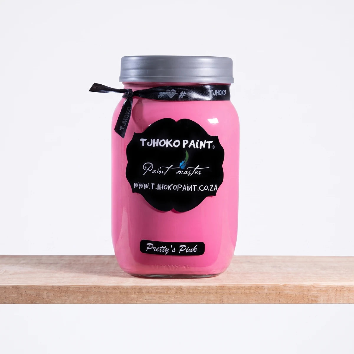 Pretty's Pink 1L Chalk Paint in a glass jar, featuring a black label, displayed on a wooden shelf.