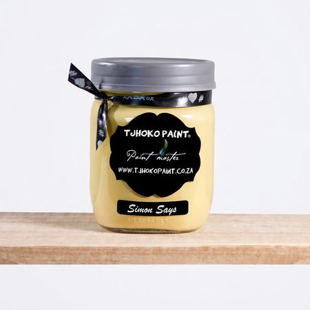 Simon Says 500ml Chalk Paint, yellow-cream paint in a clear glass jar with a black label, silver lid, and black ribbon bow.