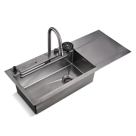 Stainless steel kitchen sink with single-handle faucet, cup rinser, and accessory tray, angled view.